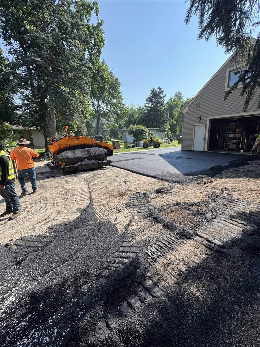 Paver laying hot mix on a wide residential driveway
